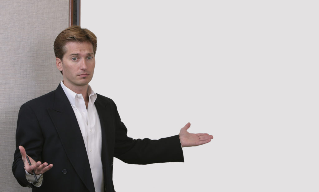 confused or stressed business man throwing hands up in front of a white board